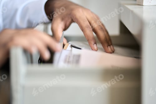 Preview: Male hands searching corporate documents files in archive drawer.