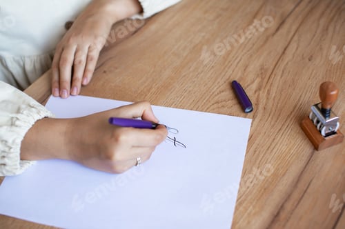 Preview: Person Writing Letter at Wooden Desk with Pen and Stamp