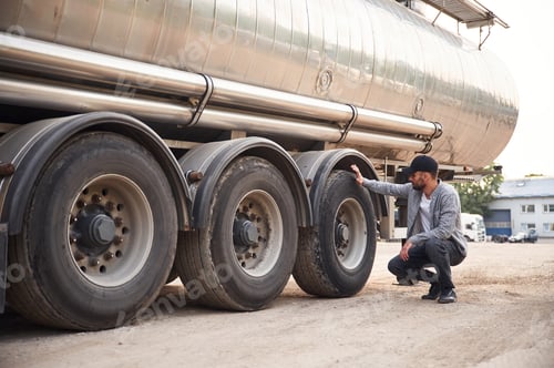 Preview: Checking the wheels. Young truck driver in casual clothes