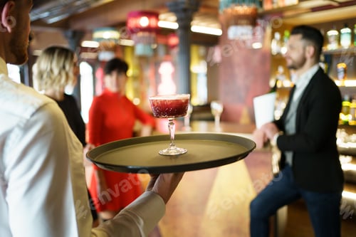 Preview: Waiter serving a cocktail for elegant clients in a nice bar