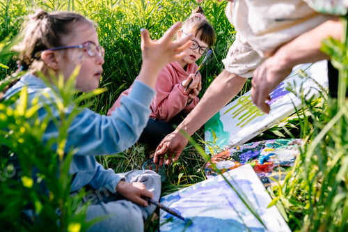 Preview: children with Down syndrome as they paint wildflowers on canvases in a sunny meadow