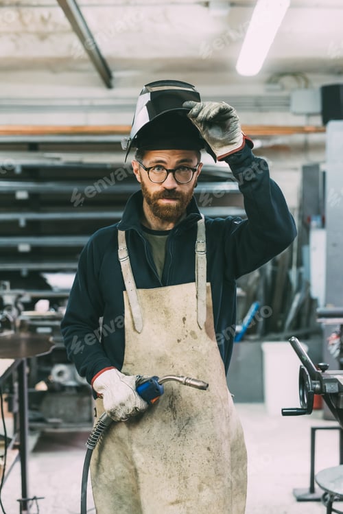 Preview: Portrait of metalworker holding welding torch in forge workshop