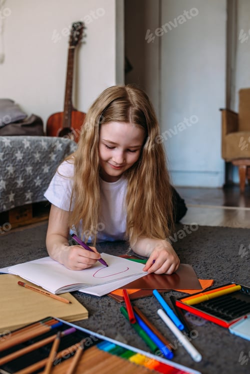 Preview: The girl after school plays at home, draws with pencils and felt-tip pens on paper.