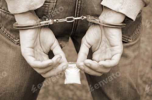 Preview: Arrested drug dealer in police handcuffs with small heroin drug