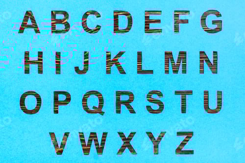 Preview: The letters of the English alphabet are carved from blue cardboard, a wooden background