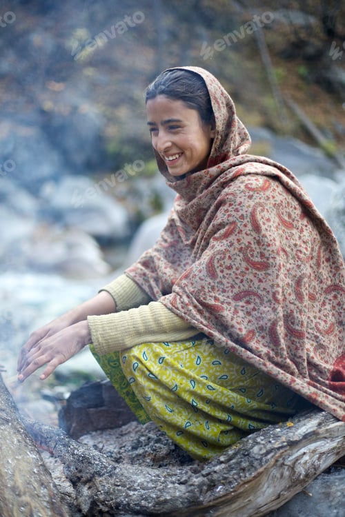 Preview: Woman enjoying the warmth of a campfire outdoors