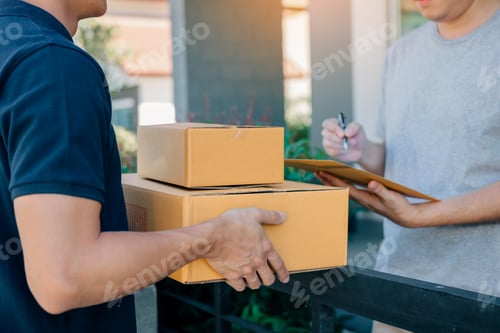 Preview: Delivery young man standing at the door of home and carrying parcels for young male to signing.