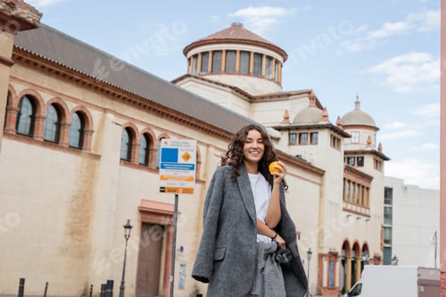 Preview: Smiling Woman Holding Orange in City Urban Setting