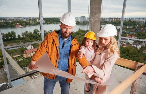 Preview: Family with child studying building plan at construction site.