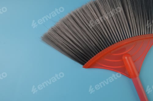 Preview: Close up view of red black broom isolated on a blue background