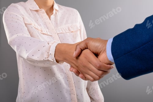 Preview: Mid section of businessman and businesswoman shaking hands against grey background