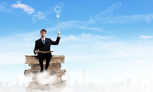 Preview: Young Businessman Sitting On Pile Of Books
