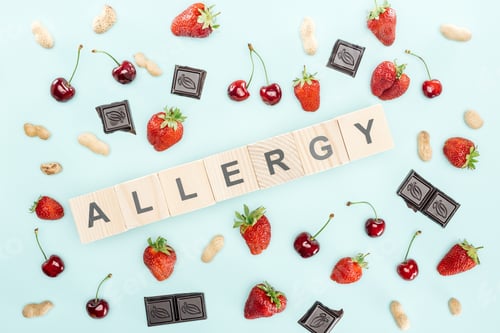 Preview: top view of wooden blocks with allergy lettering near cherries, nuts, strawberries and chocolate