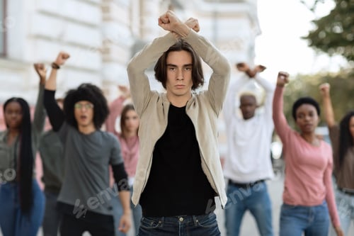 Preview: Young man leading multiracial group of activists, crossing fists up
