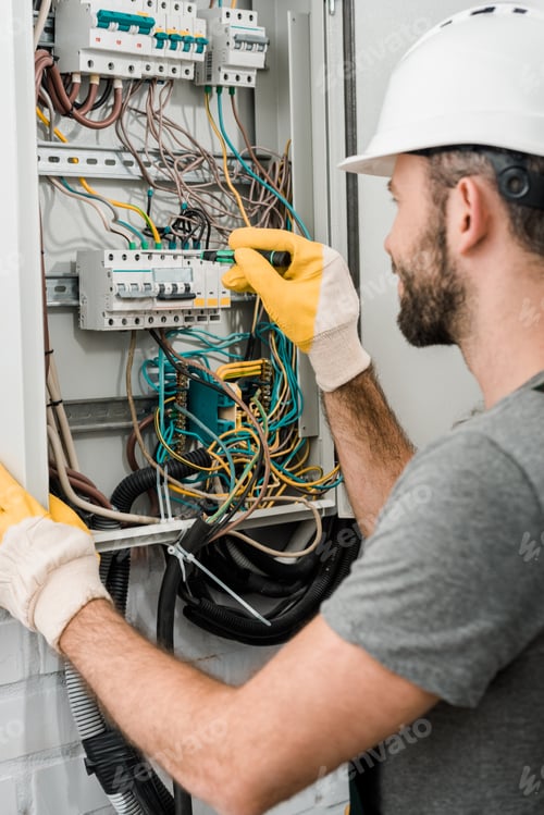 Preview: side view of electrician repairing electrical box and using screwdriver in corridor