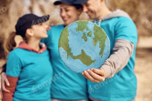 Preview: Close-up of family of volunteers holding planet Earth placard.