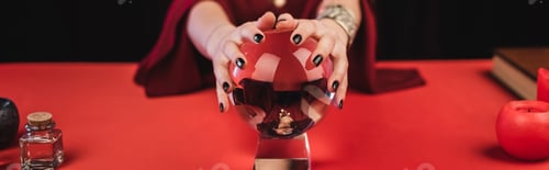 Preview: Cropped view of medium touching glass orb near candles isolated on black, banner