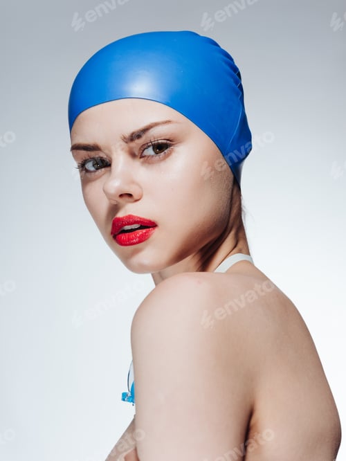 Preview: Side view of a beautiful woman in a blue swimming cap, naked shoulders