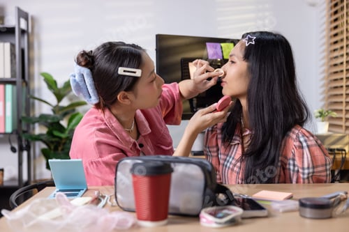 Preview: Woman applying makeup on friend indoors