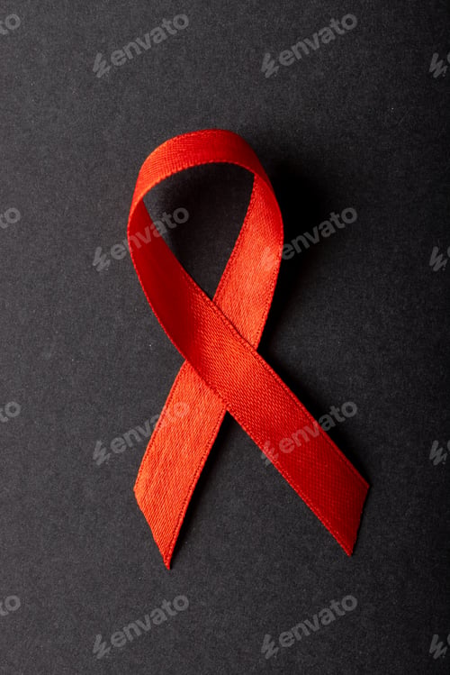 Preview: Overhead close-up of red aids awareness ribbon isolated against black background, copy space