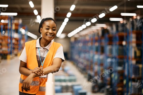 Preview: Happy African American female worker at industrial storage compartment.