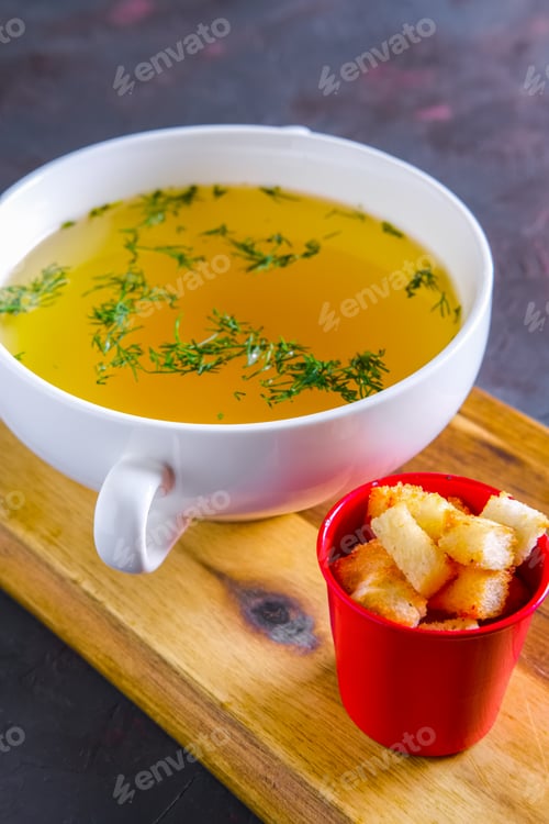 Preview: Plate with clear soup and pieces of white bread crouton