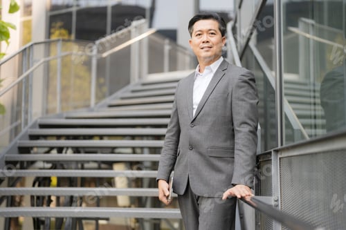Preview: Confident businessman standing outdoors by staircase