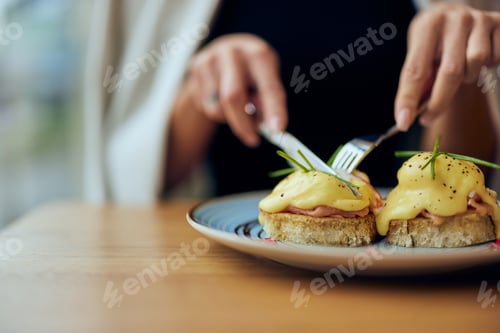Preview: Close-up of a female hands, cutting an egg toast in half, using a fork and a knife.