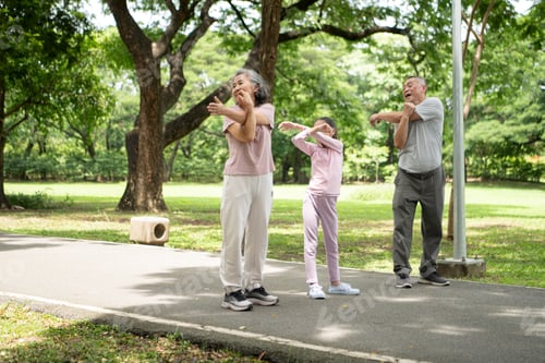 Preview: Happy Asian grandparents and granddaughter running joyfully together in a park,