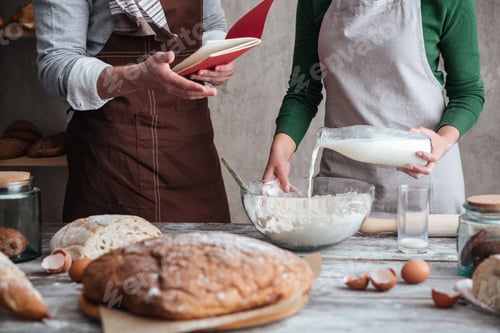 Preview: Loving couple bakers standing near bread and cooking.