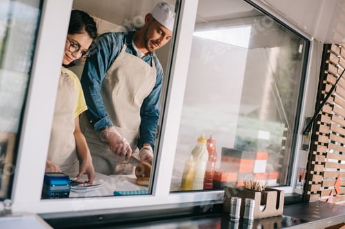 Preview: smiling young male and female workers working together at food truck