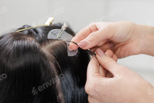 Preview: Hair extensions installation close up with micro bead method at crown in salon