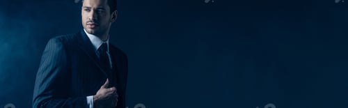 Preview: Confident mafioso looking away on dark background, panoramic shot