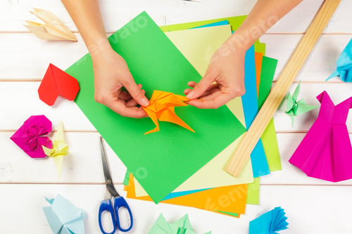 Preview: Creating paper crafts with colorful paper and hands engaged in folding