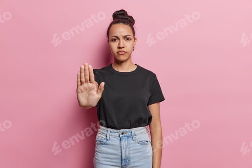Preview: Serious Latin woman shows stop gesture with palm asserts boundaries sends message of resistance has