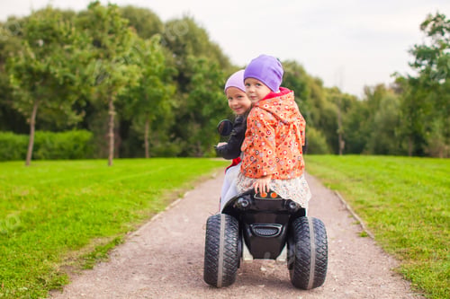 Preview: Portrait of adorable little girls ride a motorbike in green park