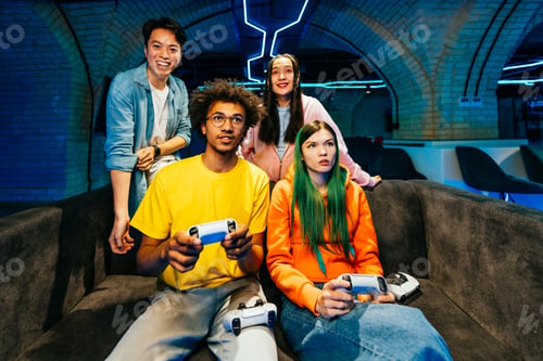 Preview: Multiethnic group of young friends playing videogames at home