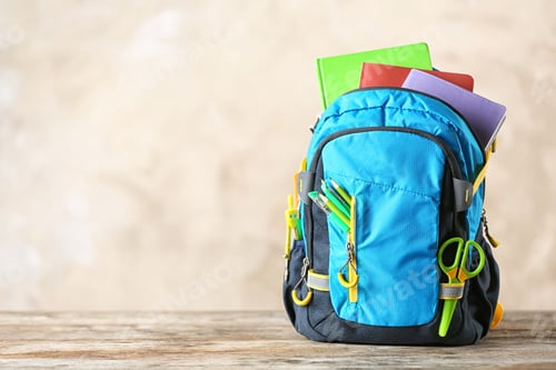 Preview: Backpack with school stationery on table against color background