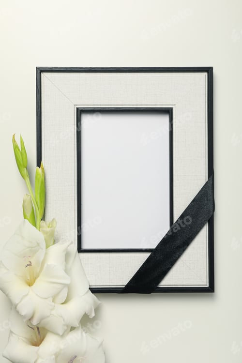 Preview: Photo frame with black ribbon and flower on white background, top view