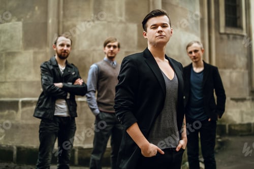 Preview: stylish handsome group of men standing and posing on the background of city street