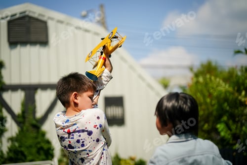 Preview: Portrait of kid in pilot costume holding wooden plane running in summer field. kid playing.