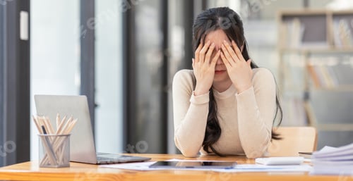 Preview: Stressed business asian woman working from at workplace on laptop looking worried, tired and overwhe