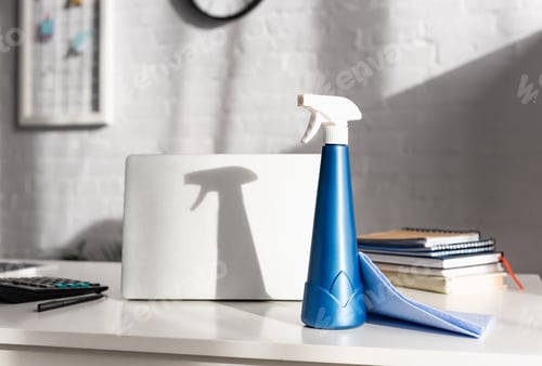 Preview: Detergent and rag near laptop and calculator on blurred foreground on table