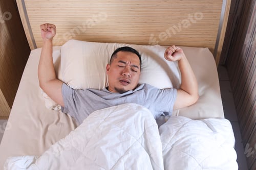 Preview: man sleeping waking up and stretching in his bed