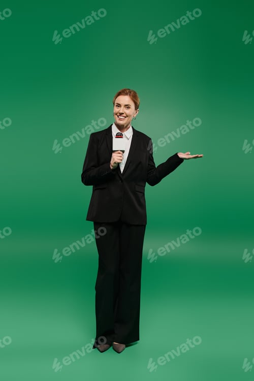 Preview: TV presenter in black attire speaks on green backdrop