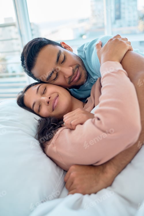 Preview: Loving mixed race couple hugging while lying in bed together. Handsome young man hugging his girlfr