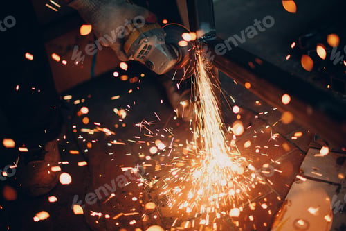 Preview: Craftsman sawing metal with disk grinder saw in workshop