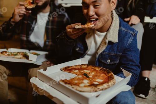 Preview: asian male eating pizza with friends at night