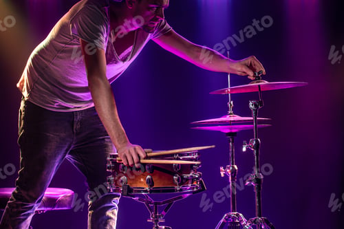 Preview: The drummer plays the drums. Beautiful blue and red background, with rays of light.