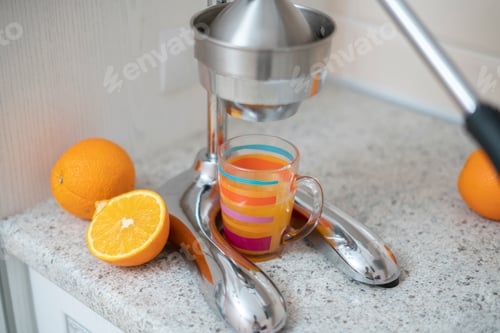 Preview: steel metal manual press juicer with cut oranges and glass on the kitchen table at home